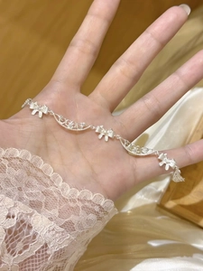 Détail d'un bracelet noeud argenté avec maillons en filigrane et petits zircons