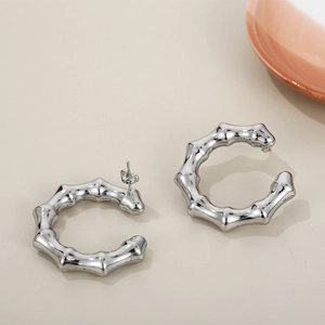 Close-up of silver C-shaped bamboo texture earrings in polished stainless steel