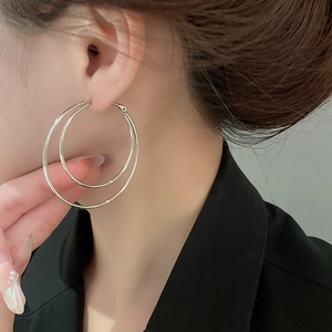 Close-up of model wearing minimalist silver double-layer hoop earrings with glossy finish