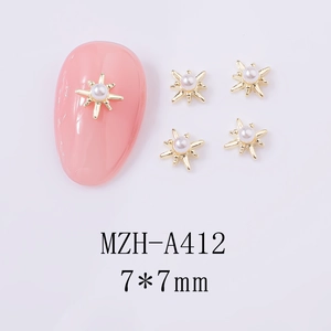 Macro view of 7x7mm gold starburst cross nail charms with white pearl inlay center