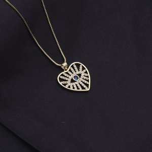 Golden heart necklace with evil eye pendant and blue gemstone on black background