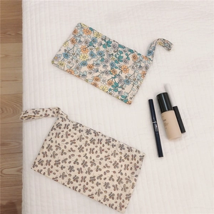 Flat lay of floral cotton pouch sets with makeup accessories on white background