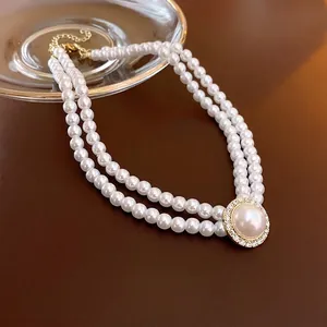 Double-layered pearl necklace with oval pendant and sparkling rhinestones on leather background