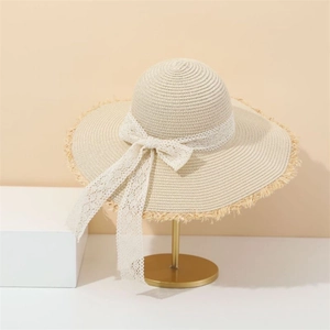 Close-up of cream straw sun hat featuring elegant lace ribbon and fringe brim detail