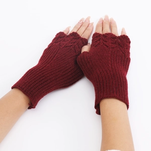 Close-up of deep red knitted fingerless gloves with detailed fish scale pattern texture