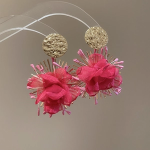 Detail of rose red chiffon flower earrings with golden hammered metal texture on display