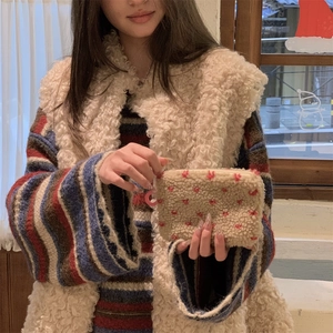 Detail of plush beige pouch with strawberry embroidery and pink round zipper pull