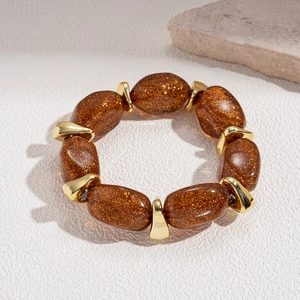 Detailed shot of amber acrylic oval beads with golden glitter and metallic spacers