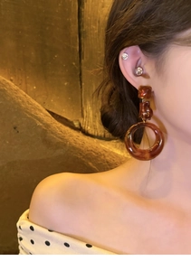 Close-up of amber brown resin hoop earrings with gold links worn by a female model