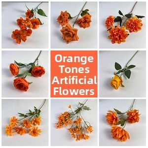 Collection of orange artificial flowers including roses and daisies for wedding decor