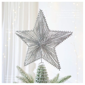 Sparkling silver glitter star tree topper with sequins on a snowy Christmas tree branch