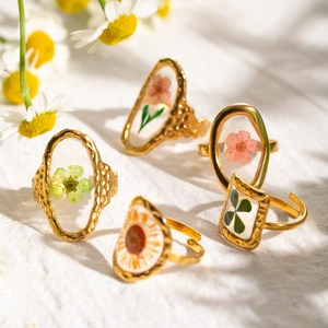 Gold stainless steel rings featuring real dried flowers in transparent resin settings
