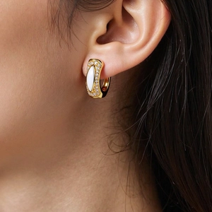 Detail von 18K vergoldeten Creolen mit Marquise-Stein und Zirkonia am Ohr des Models
