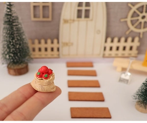 Makroaufnahme eines Miniatursacks mit roten Beeren auf der Fingerspitze für Puppenhäuser
