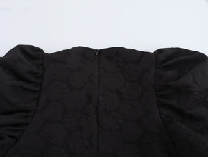 Detail der schwarzen Rosen-Jacquard-Stoffstruktur und des verdeckten Reißverschlusses