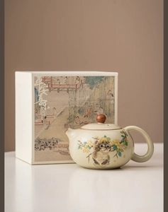 Detailed view of ceramic teapot with cat and flower patterns in an elegant gift box