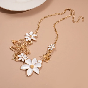 Detail of gold flower necklace with white enamel petals and textured metallic floral centers