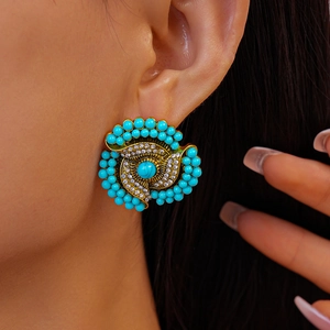Macro shot of retro gold flower earrings with turquoise beads and clear rhinestones