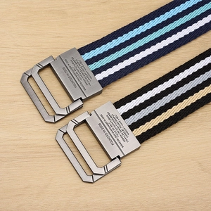 Detail of striped canvas belts with brushed metal D-ring buckles on wooden surface