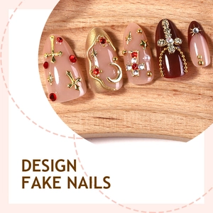 Luxury almond press-on nails with red rhinestones, gold crosses, and pearls on wood