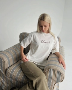 Détail d'un t-shirt blanc en coton avec broderie Cheers marron et col rond côtelé