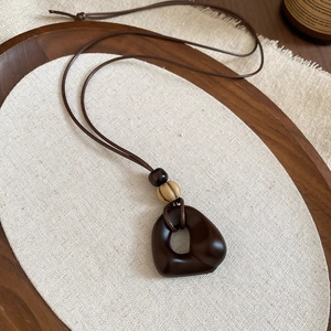 Detailed view of vintage brown resin geometric pendant necklace on rustic linen