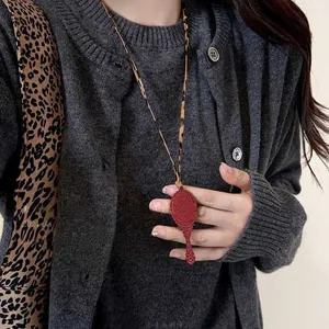 Close-up of vintage red embossed mirror pendant with leopard print faux leather cord