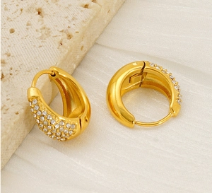 Gros plan de boucles d'oreilles créoles dorées avec pavage de zircones scintillantes