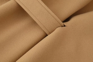 Macro detail of camel wool coat showing premium fabric texture and belt loop stitching