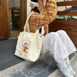 Close-up of beige canvas tote bag with embroidered cat pattern and 'Light' text detail