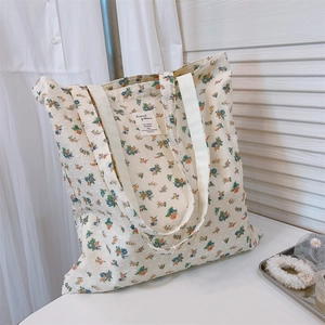 Close-up of floral cotton tote bag featuring blue and orange patterns on cream fabric