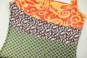 Dettaglio di abito aderente stampato con motivi paisley, floreali e a quadretti verdi