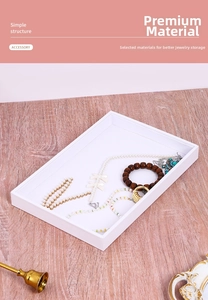 Detailed top view of a white minimalist jewelry display tray holding pearls and rings