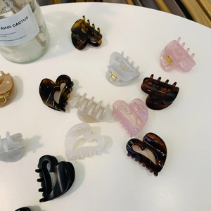 Hollow heart acetate hair claws in various colors arranged on white surface