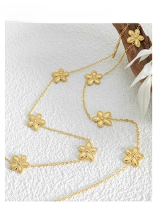 Detailed view of a gold daisy pendant necklace on a white textured backdrop