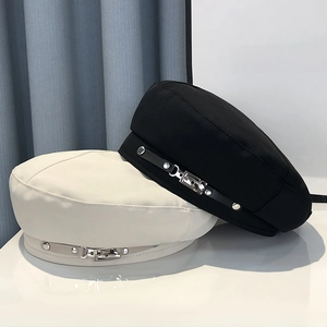 Detail of flat top beret caps with leather straps and silver metal buckle accents
