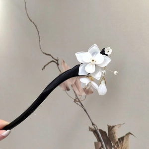 Close-up of a magnolia flower hair stick with elegant white petals and golden tassels