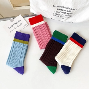 Detail of color-block ribbed crew socks in four stylish colorways on minimalist background