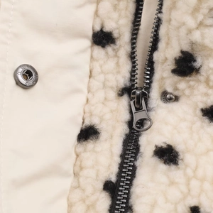 Détail macro du tissu crème et doublure polaire avec fermeture éclair et bouton en métal