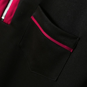 Detail eines Herren-Poloshirts aus schwarzem Piqué mit kontrastierendem rosa Reißverschluss