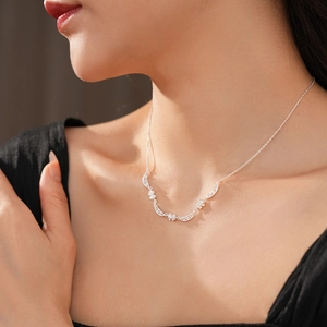 Detailed view of a silver bow necklace with sparkling crystals on a model's neck