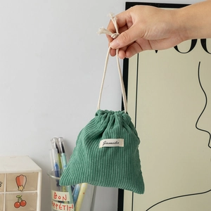 Detail of green corduroy drawstring pouch showing soft ribbed texture and cotton cord closure