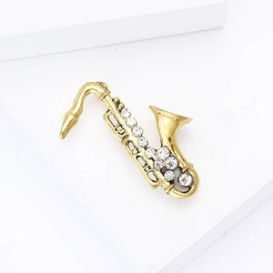 Detailed view of a gold saxophone brooch with inlaid rhinestones on a white stand