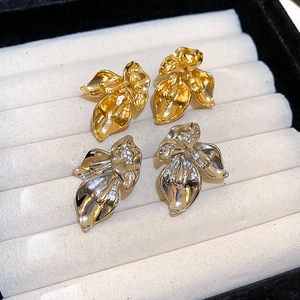 Macro shot of gold and silver calla lily stud earrings with sleek metallic texture