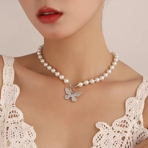 Detailansicht der weißen Perlenkette mit silbernem Schmetterlingsanhänger am Model