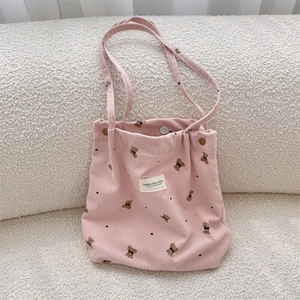Detail of pink corduroy tote bag featuring a cute bear print and white canvas brand label