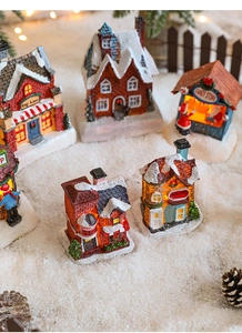 Detail of miniature Christmas resin village with warm LED lights on artificial snow
