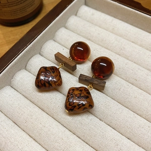 Détail de boucles d'oreilles vintage en bois et résine léopard dans un écrin