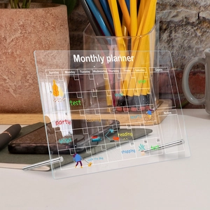Detailed view of acrylic monthly planner with white grid and metal support stands