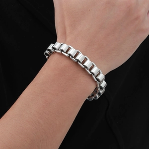 Close-up of polished silver stainless steel link chain bracelet worn by a male model